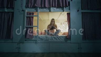 年轻漂亮的女人坐在宿舍房间的床上，用完智能手机，就要睡觉了